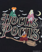 Close-up of Hocus Pocus embroidery design with witches flying on a broomstick, bats, and crescent moon on a black sweatshirt