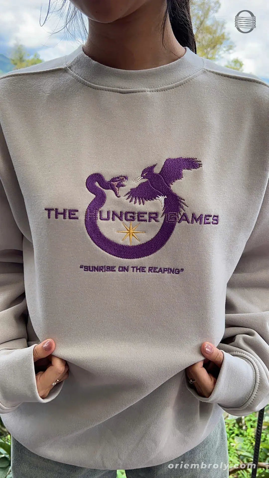 Front view of model wearing sand color Hunger Games Sunrise on the Reaping embroidered sweatshirt