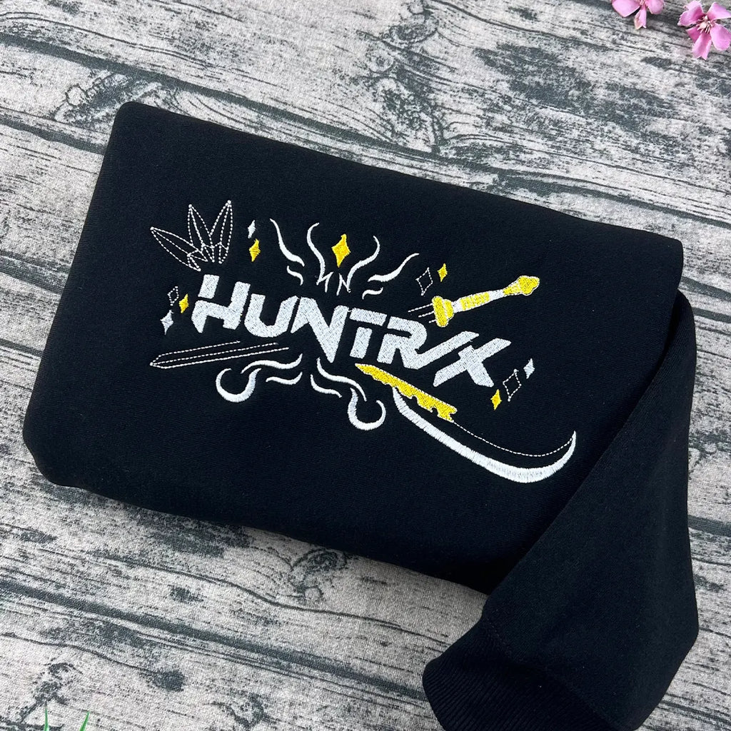 Black t-shirt with 'HUNTRK' logo on a wooden surface