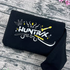 Black t-shirt with 'HUNTRK' logo on a wooden surface