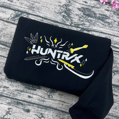 Black t-shirt with 'HUNTRK' logo on a wooden surface