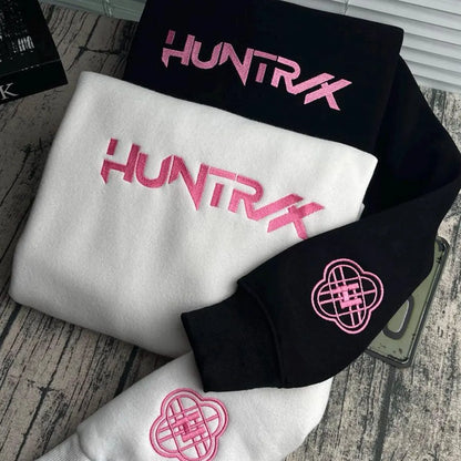Black, white, and pink 'HUNTRX' branded items on a wooden surface