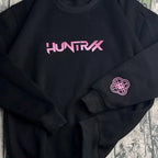 Black sweatshirt with pink 'HUNTRX' logo on a textured surface