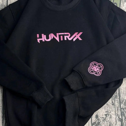 Black sweatshirt with pink 'HUNTRX' logo on a textured surface
