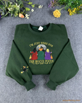 Flat lay of a forest green Halloween crewneck sweatshirt embroidered with Im Just Here For The Hocus Pocus and witches