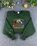 Flat lay of a forest green Halloween crewneck sweatshirt embroidered with Im Just Here For The Hocus Pocus and witches