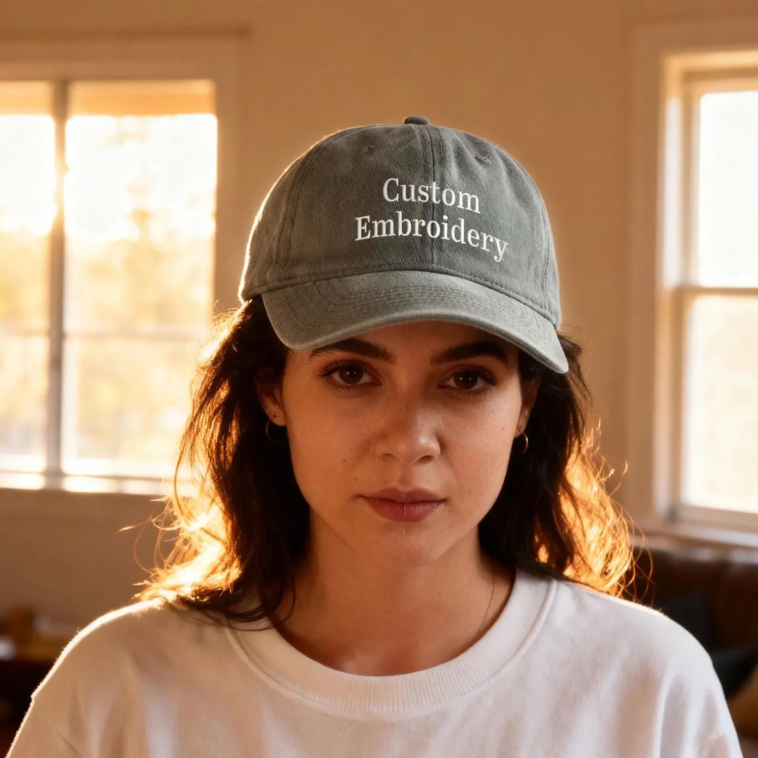 Person wearing a cap with 'Custom Embroidery' text in a room with windows.