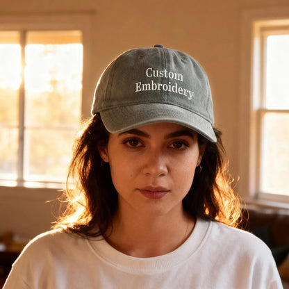Person wearing a cap with 'Custom Embroidery' text in a room with windows.