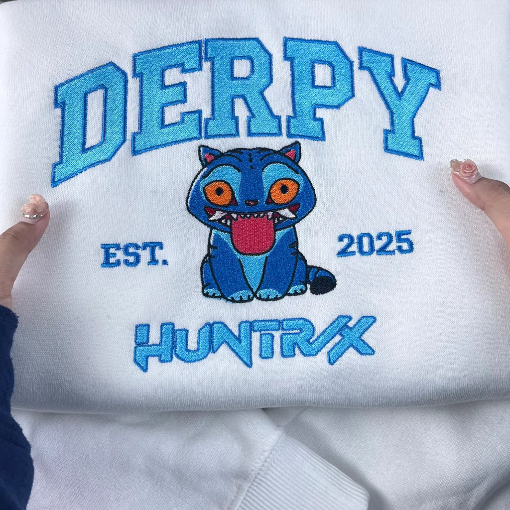White sweatshirt with blue embroidered text and a cartoon character on a white background