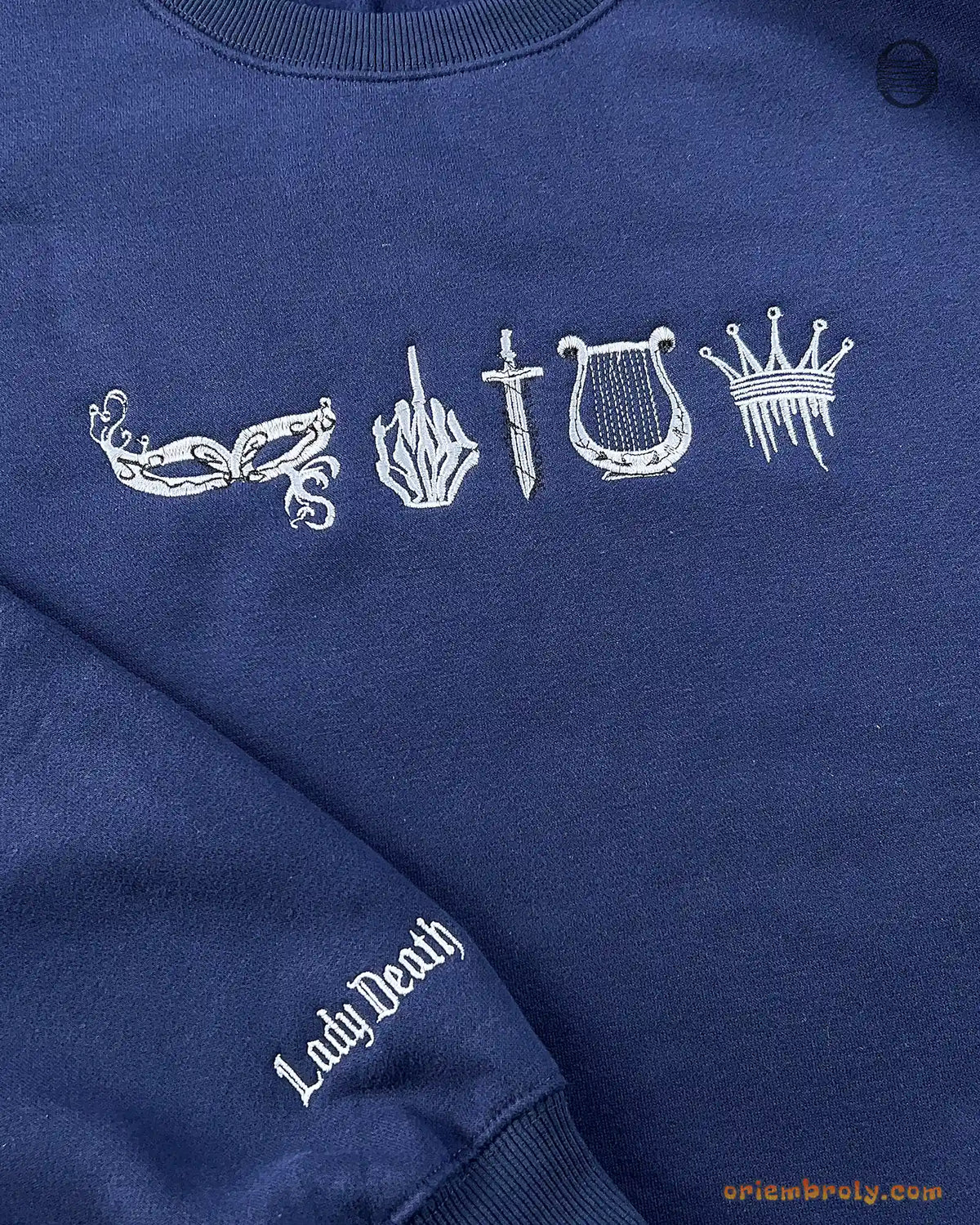 Close-up of silver gothic symbols embroidery across the chest on a navy blue sweatshirt