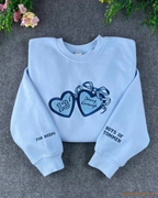 Light blue crewneck sweatshirt featuring dark blue embroidered bow hearts and Best of Friends sleeve detail