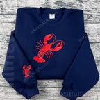 Navy blue sweatshirt with red lobster design on a gray wooden surface