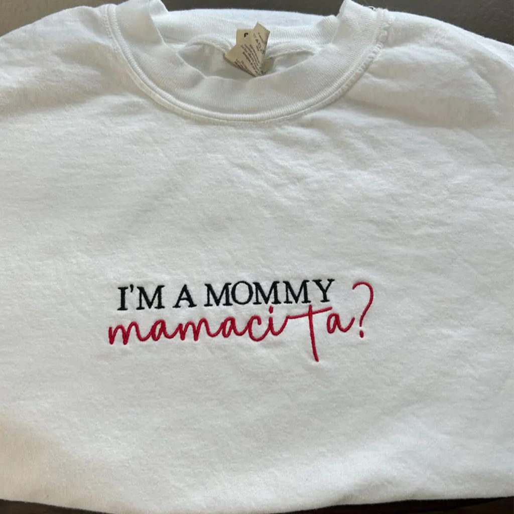 White sweatshirt with text 'I'm a mommy mamacita?' on a plain background