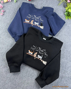 Flat lay of black and navy blue Halloween embroidered crewneck sweatshirts with witchy cats design