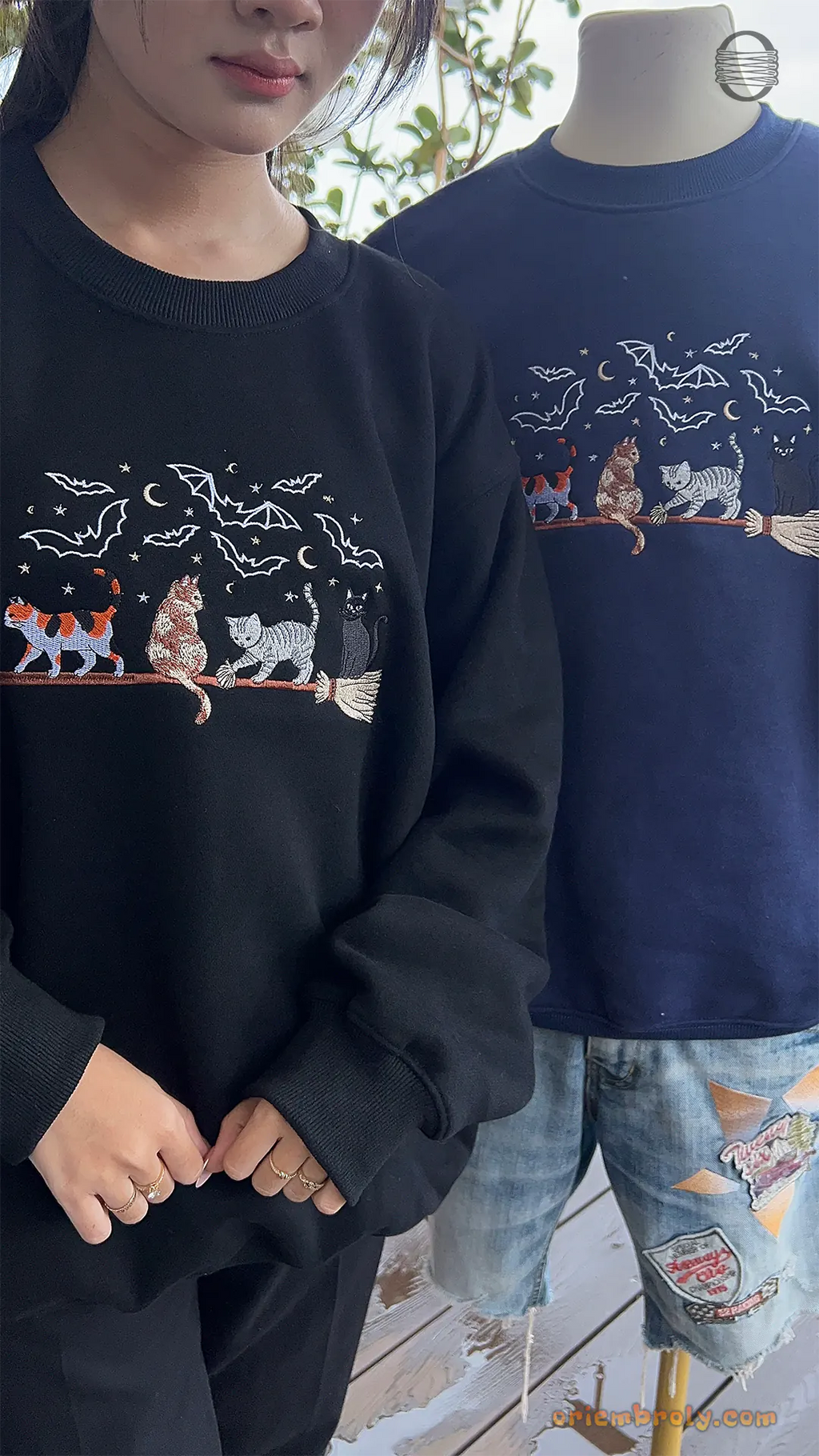 Two models wearing matching black and navy blue Halloween witch cat embroidered sweatshirts