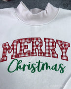 Close-up of red plaid Merry Christmas embroidered text on a white crewneck sweater
