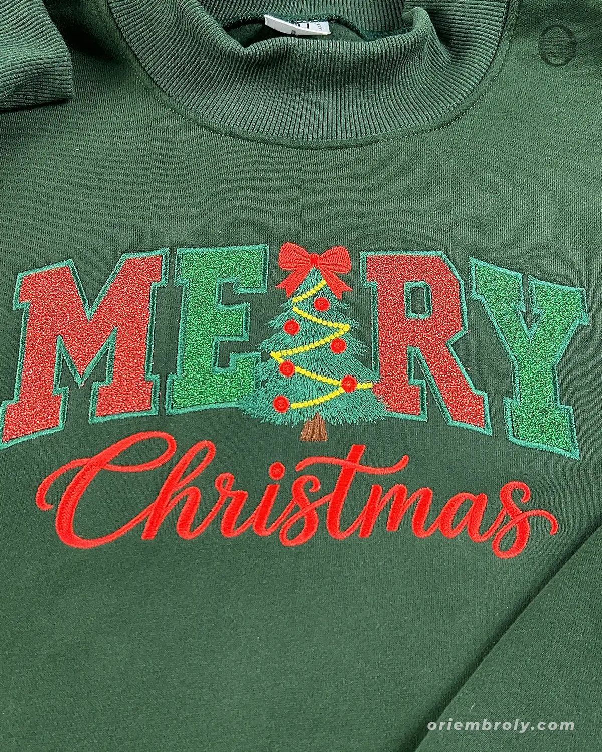 Close-up of red and green Merry Christmas embroidery with Christmas tree letter R design on a forest green sweater