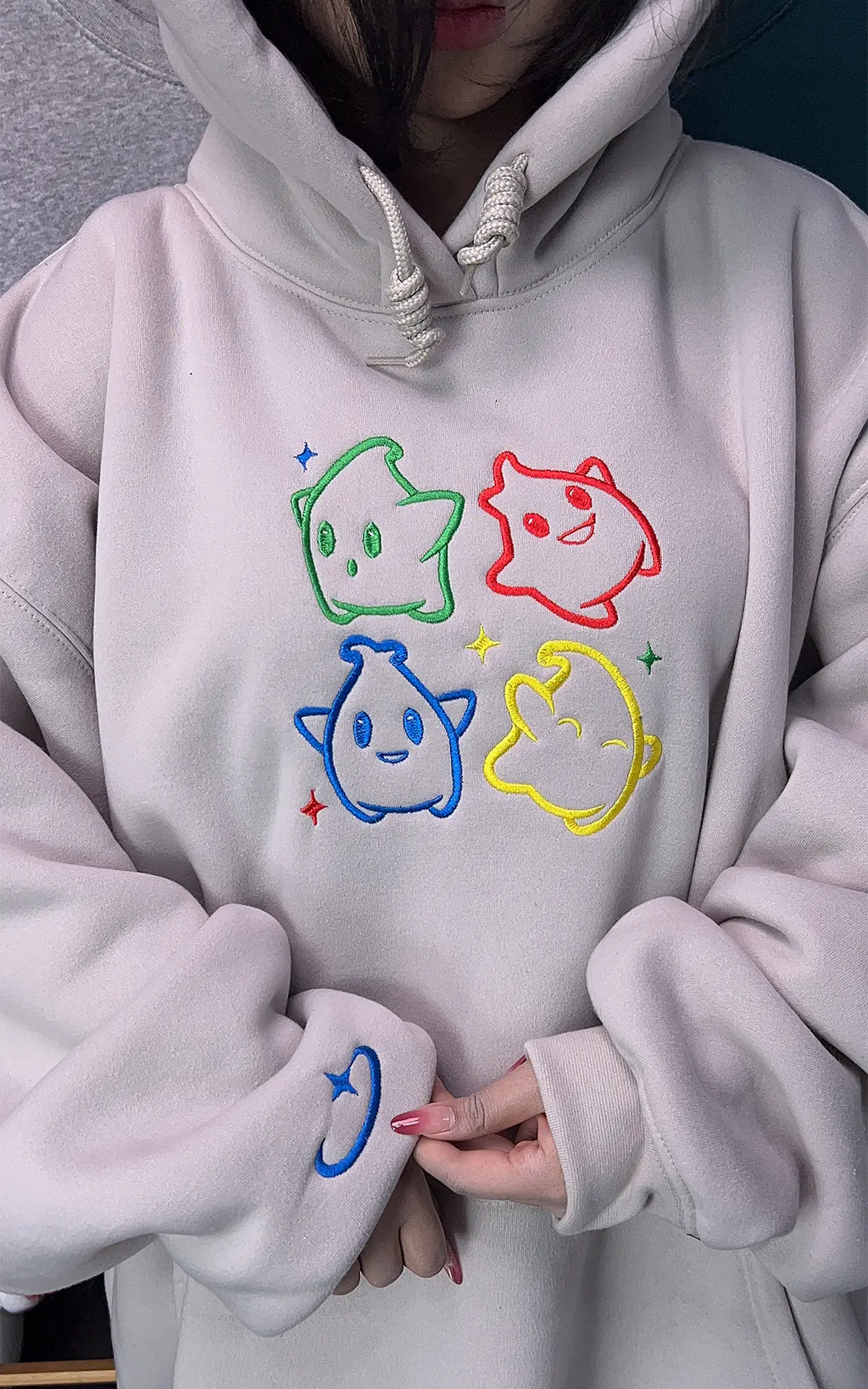 Minimalist Nintendo-inspired apparel: White hoodie with embroidered Luma icons in primary colors.