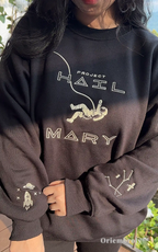 Minimalist sci-fi streetwear: black crewneck with detailed astronaut and cosmic sleeve embroidery. Narrative-driven apparel inspired by modern literature and outer space exploration, perfect for a clean, aesthetic look