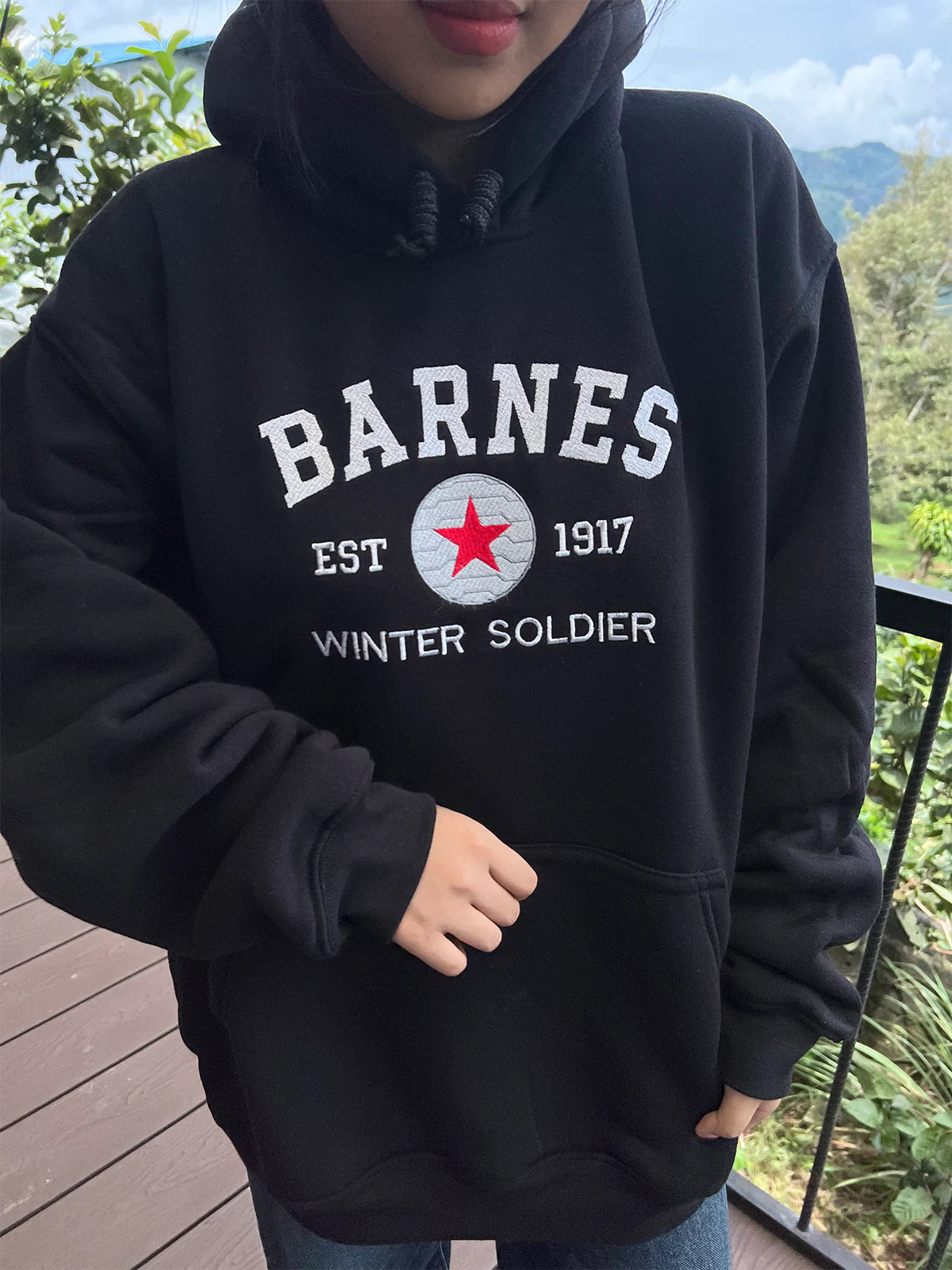 Person wearing a black hoodie with 'Barnes' branding outdoors.