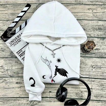 White hoodie with black designs on a wooden surface with headphones and a clapboard.