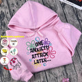 Pink hoodie with colorful text design on a wooden surface