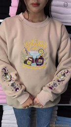 Model wearing an oversized beige Practical Magic embroidered sweatshirt with witchy frog sleeve graphics