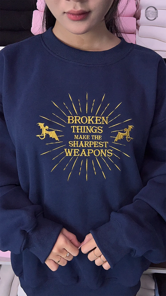 Model wearing an oversized navy blue Broken Things Make The Sharpest Weapons embroidered crewneck sweater for bookish outfit