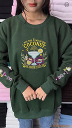 Model wearing an oversized forest green Practical Magic embroidered sweatshirt with dual sleeve graphics