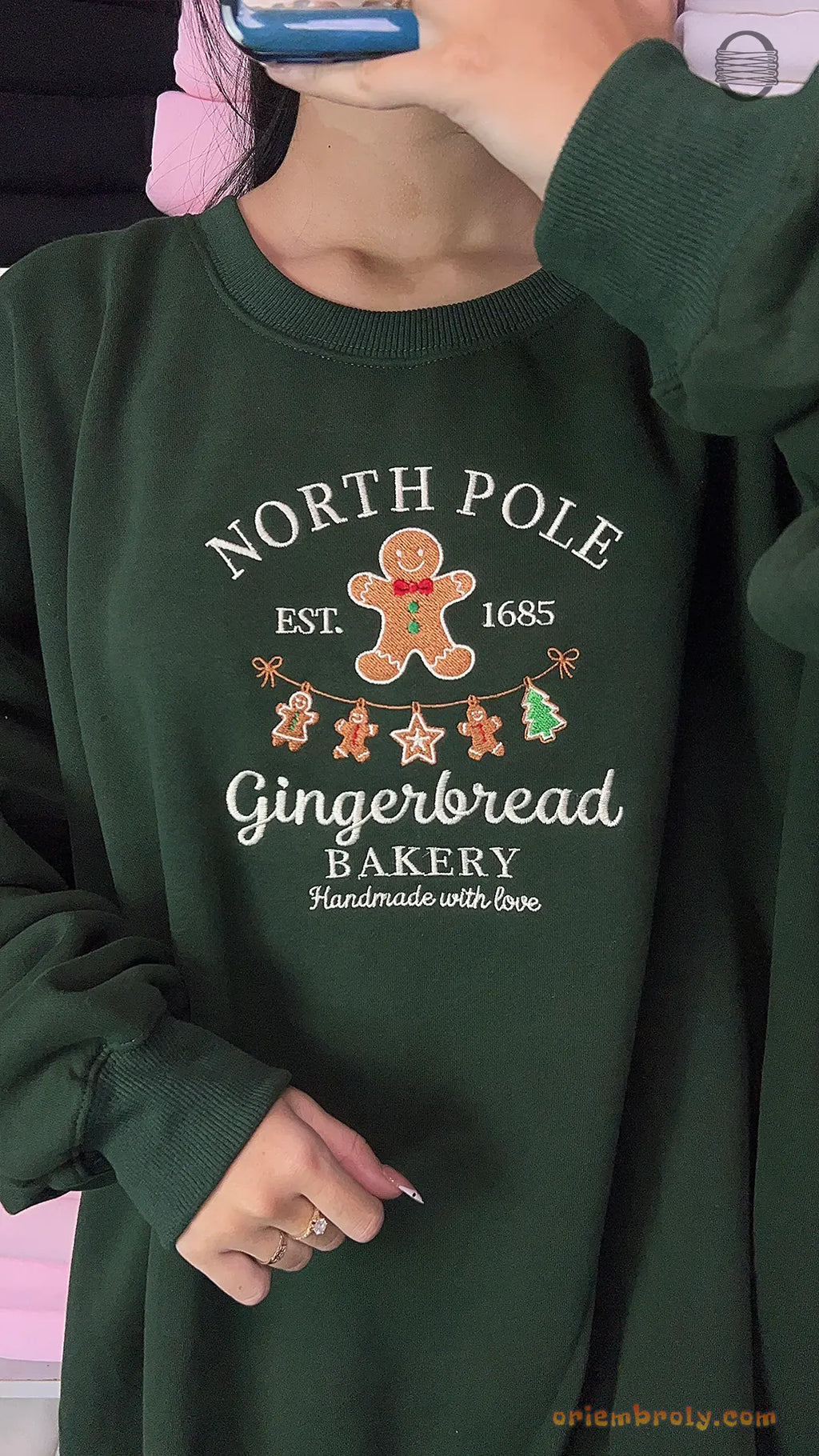 Model wearing an oversized forest green North Pole Gingerbread Bakery embroidered crewneck sweater for holiday outfit