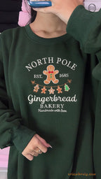 Model wearing an oversized forest green North Pole Gingerbread Bakery embroidered crewneck sweater for holiday outfit