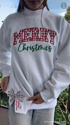 Model wearing an oversized white Merry Christmas sweatshirt showing the Christmas bow sleeve embroidery outdoors
