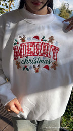 Model wearing an oversized white Merry Christmas plaid embroidered sweater in natural outdoor lighting