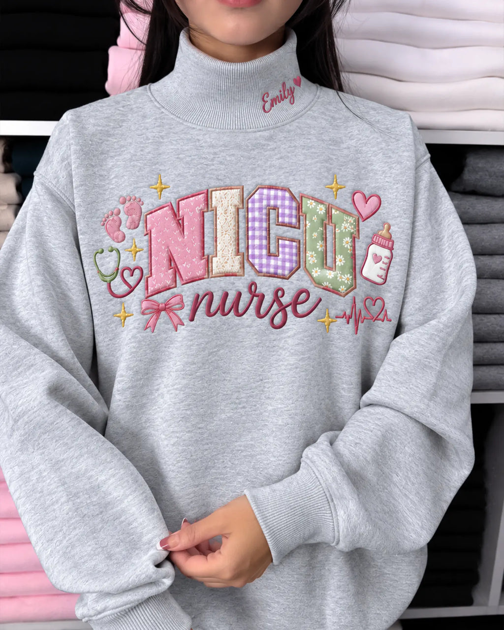 Model wearing an oversized sport grey NICU nurse embroidered crewneck sweatshirt showing detailed pastel letters and ribbon bow