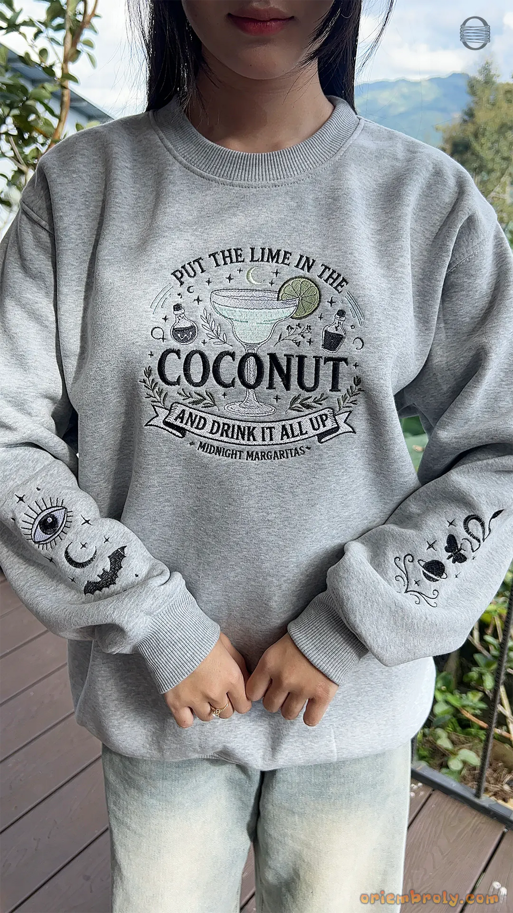 Model wearing an oversized grey Practical Magic Put The Lime In The Coconut embroidered sweatshirt