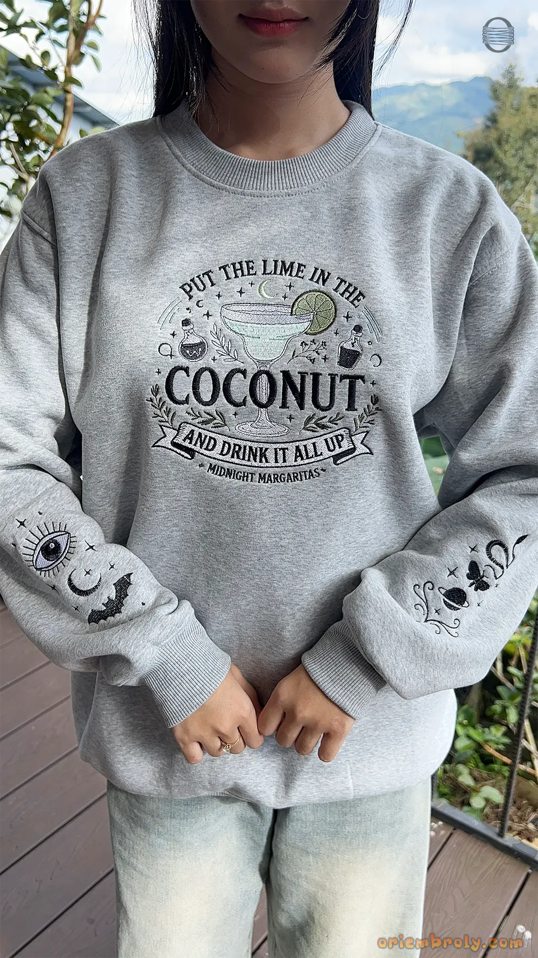 Model wearing an oversized grey Practical Magic Put The Lime In The Coconut embroidered sweatshirt