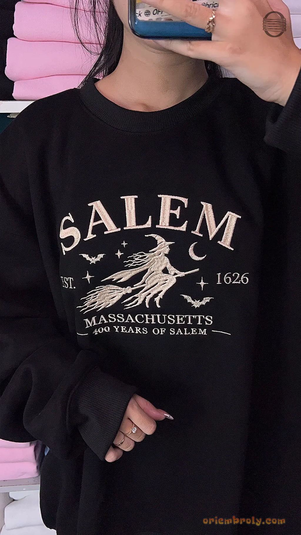 Model wearing an oversized black Salem Massachusetts flying witch embroidered crewneck sweater for Halloween outfit