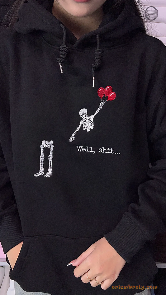 Model wearing an oversized black hoodie featuring funny skeleton floating with red balloons embroidery