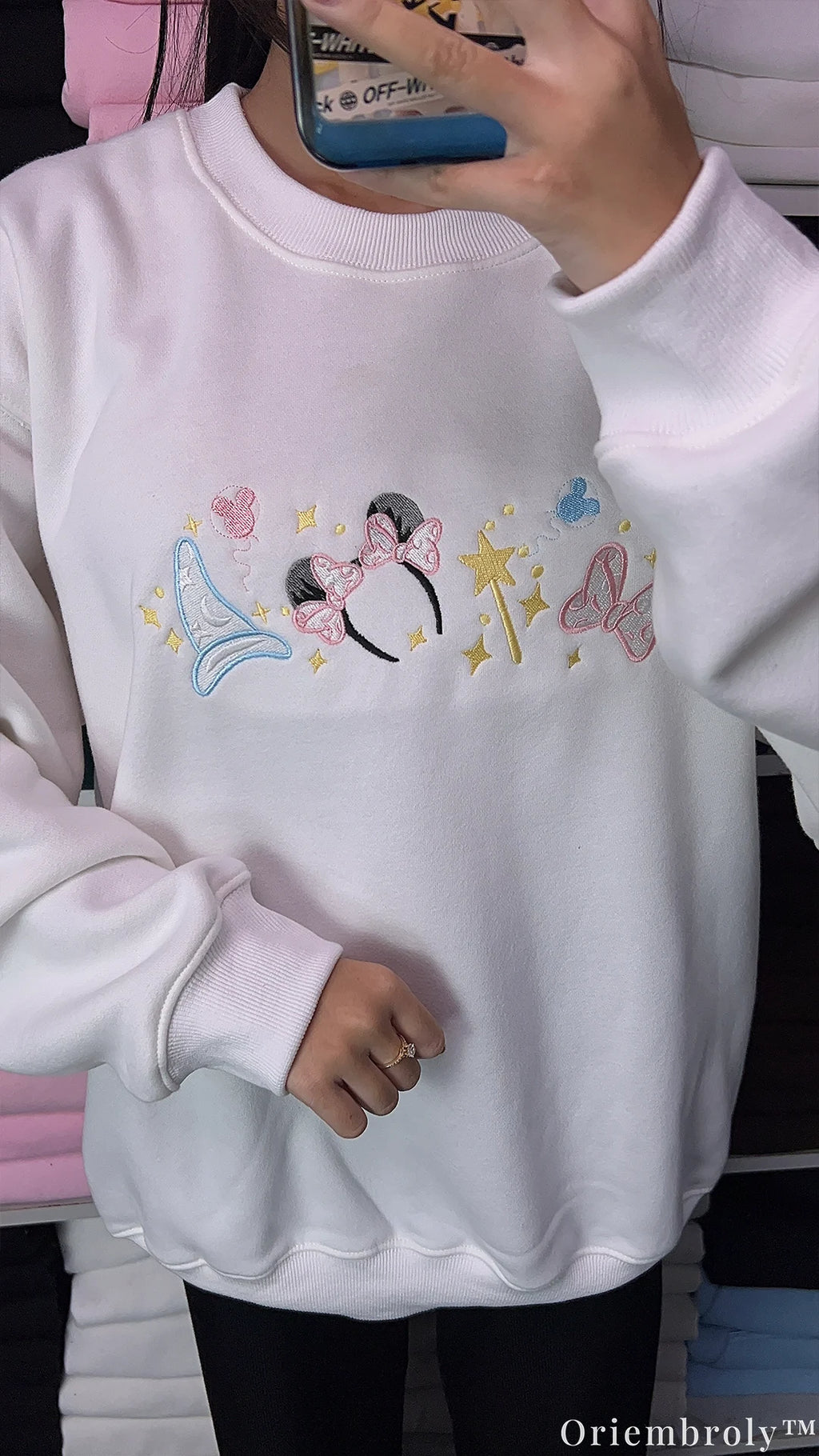 Model wearing an oversized white Disney magical embroidered sweatshirt paired with dark pants