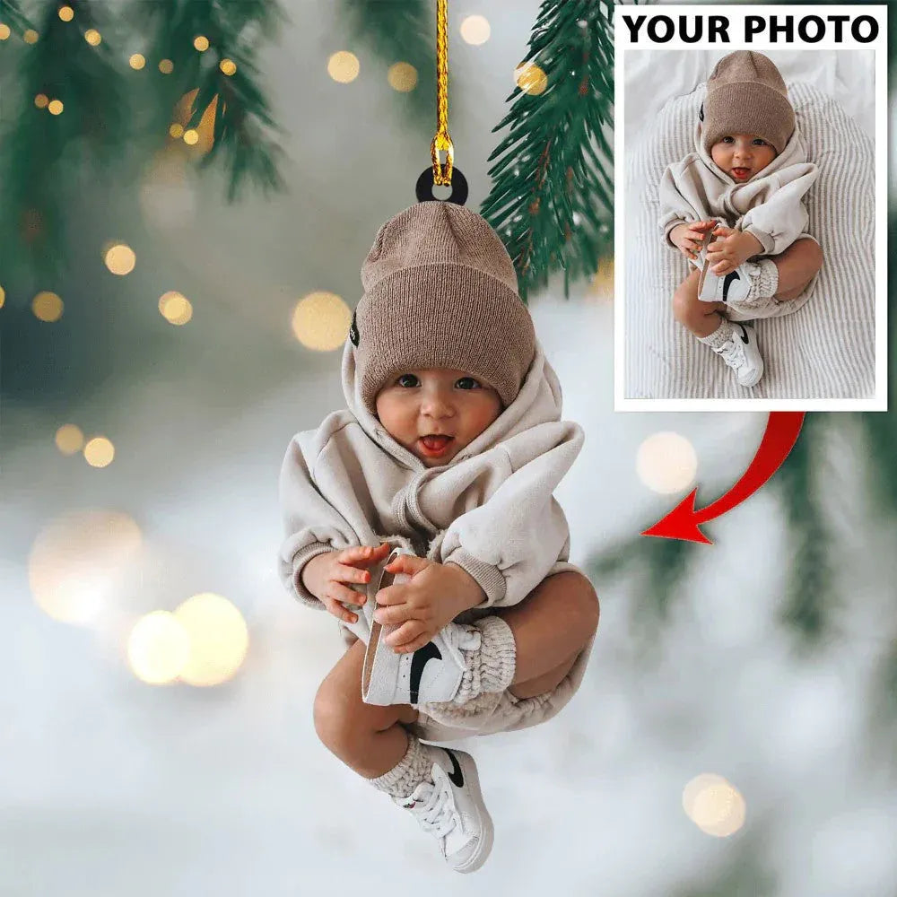 A custom-shaped acrylic photo ornament featuring an adorable baby in a beanie, suitable as a "baby's first Christmas" keepsake or new parent gift. 