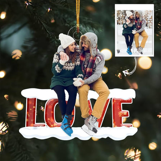 A personalized Christmas ornament featuring a couple sitting on a 'LOVE' sign, with an inset photo, suitable as a 'Our First Christmas Together' or newlywed gift.