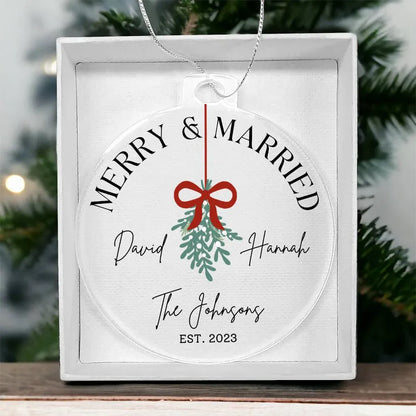 A personalized, round, clear acrylic 'Merry & Married' Christmas ornament featuring a mistletoe design and the names David & Hannah, The Johnsons, and the year EST. 2023.
