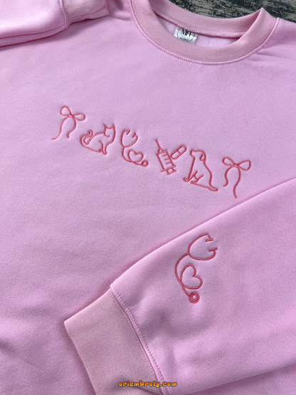 Light pink embroidered sweatshirt with cat, dog, and stethoscope designs — a cozy gift for veterinary lovers.