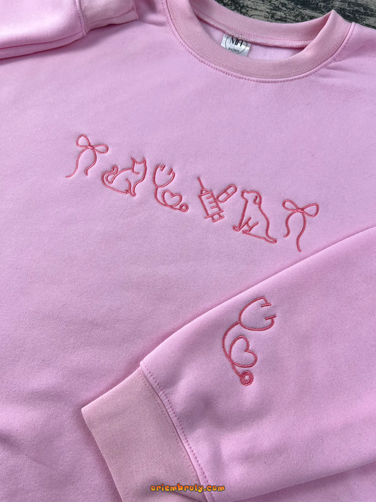 Light pink embroidered sweatshirt with cat, dog, and stethoscope designs — a cozy gift for veterinary lovers.