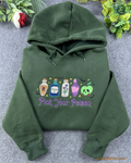 Flat lay of a forest green Halloween hoodie embroidered with Pick Your Poison and colorful witch potion bottles