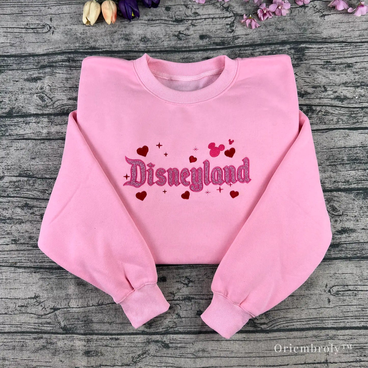Soft pastel pink sweatshirt with glitter embroidery, perfect for theme park fans and anyone who loves a little magic.