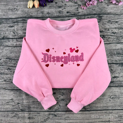 Soft pastel pink sweatshirt with glitter embroidery, perfect for theme park fans and anyone who loves a little magic.