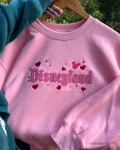 Pink embroidered sweatshirt with glitter details, designed for park lovers and those who want a magical style.