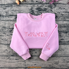 Pink embroidered sweatshirt featuring cat, dog, syringe, stethoscope, and heart designs — perfect for veterinarians or pet lovers.
