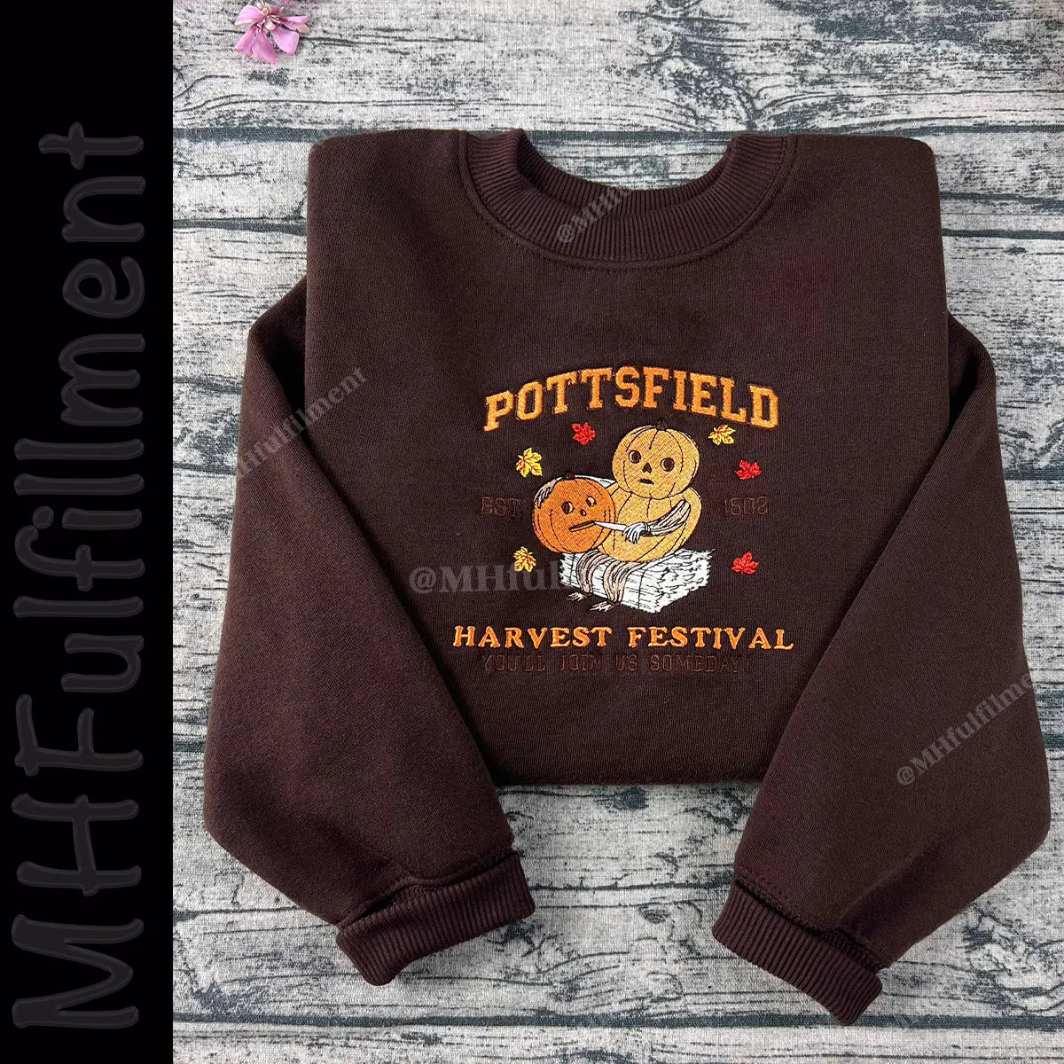Brown sweatshirt with 'Pottsfield Harvest Festival' design on a wooden surface